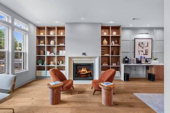 A living room with a fireplace, two chairs, and a table.